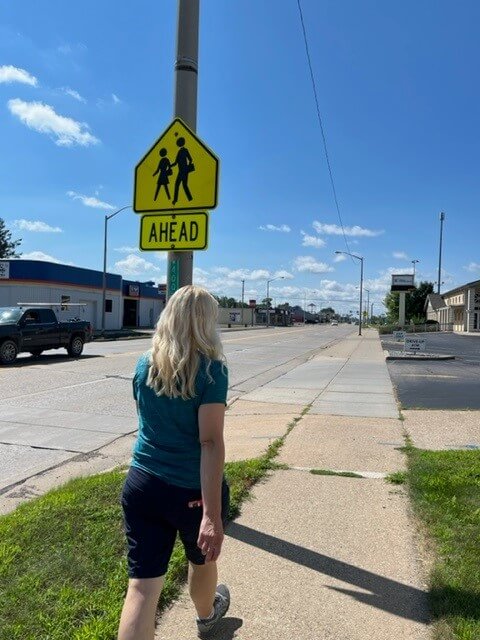 Dawn Desorcy walks along 8th Street, a typical "stroad" with wide lanes, no medians, frequent driveways, infrequent crosswalks, and other conditions that are considered hostile to pedestrians.